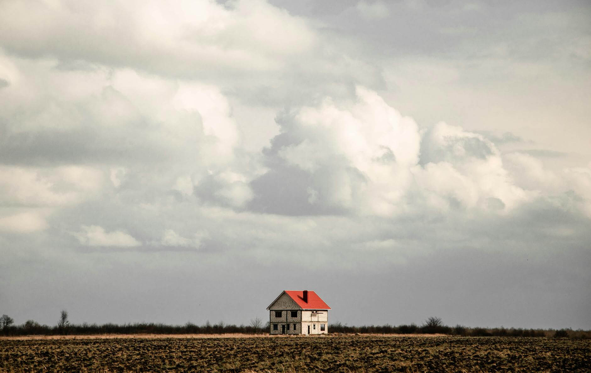 white and red house on brown field under gray sky